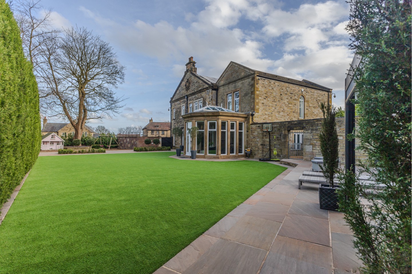 rear of large stone built house with attached orangery and spacious grounds